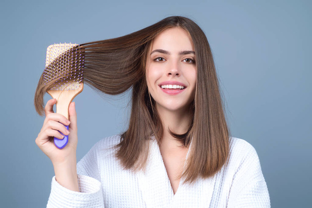 Young woman combing hair. Beautiful woman brush healthy hairs. Hairstyle and haircare concept. Girl combing and brushing hair in studio. Woman with comb combing hair. Hair brush - Фото, изображение