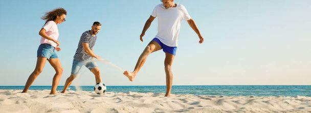 Gruppo di amici che giocano a calcio sulla spiaggia di sabbia, spazio per il testo. Design banner - Foto, immagini
