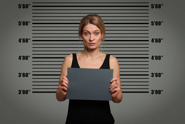 Criminal mugshot. Arrested woman with blank card against height chart - Фото, зображення