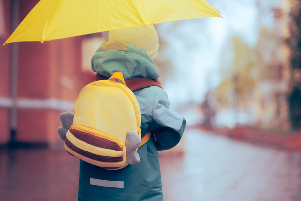 Girl with Yellow Backpack and Umbrella Going to School - 写真・画像