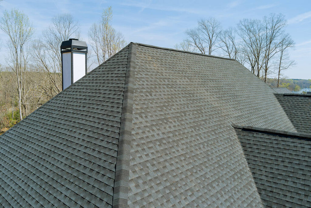 En la casa nueva, después de instalar el cubrimiento de culebrillas de asfalto, se inspecciona la calidad del trabajo del techo para asegurarse - Foto, imagen
