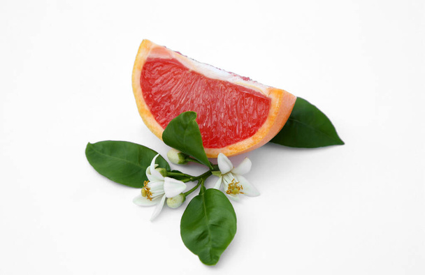 Cut fresh ripe grapefruit and green leaves on white background - Foto, Imagen