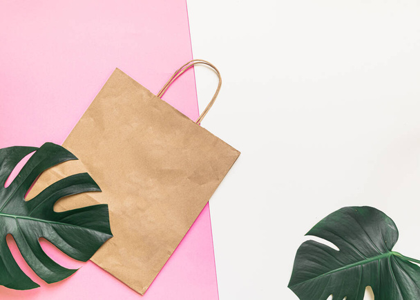 Flat Lay shopping concept with paper bag and tropical leaves. Elegant composition with elegant accessories - Photo, Image