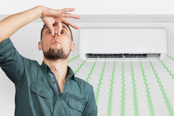 Mies haisee paha haju likainen suodatin split ilmastointilaite huoneessa. - Valokuva, kuva