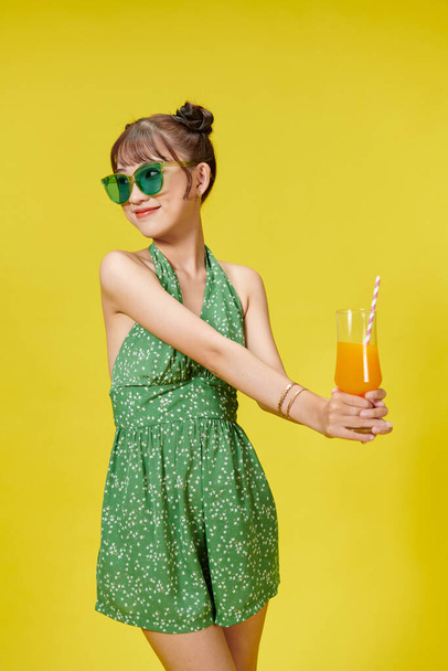 Šťastná asijská žena drží sklenici ovocné šťávy nápoj izolované na žlutém pozadí - Fotografie, Obrázek
