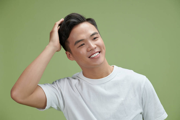 Young man smiling confident touching hair with hand up gesture, posing attractive and fashionable - Photo, Image