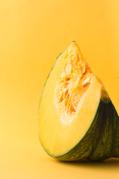 sliced pumpkin isolated on a yellowish orange background, with copy space - Foto, afbeelding