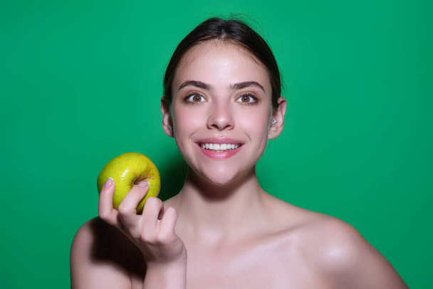 Woman bitting tasty apple. Woman eating apple, studio portrait. Morning breakfast. Woman with healthy teeth holding apples on isolated background. Healthy teeth. Dentistry, dentist and dental care - Photo, image