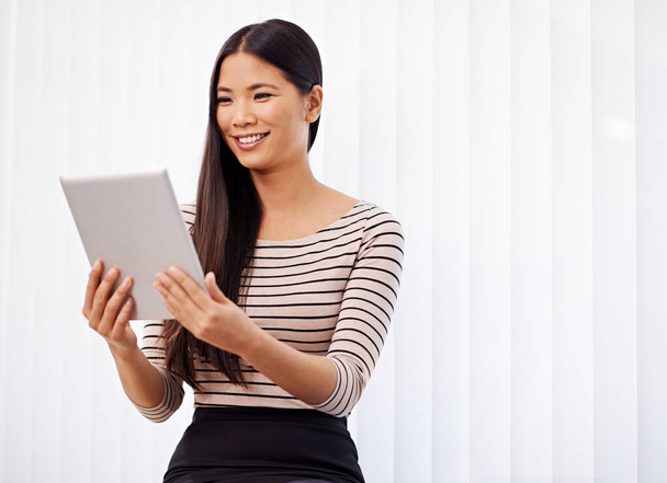 Ein Blick auf ihr Tagesprogramm. eine junge asiatische Geschäftsfrau mit einem digitalen Tablet im Büro - Foto, Bild