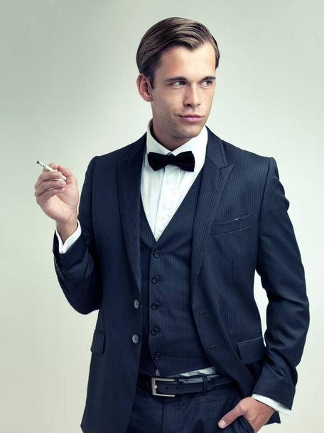 Hes never short on confidence. A studio shot of a dapper young gentleman smoking a cigarette - Фото, зображення