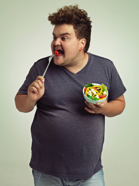 Сідайте мені в живіт. Студійний знімок надмірної ваги людини, що тримає тарілку салату
 - Фото, зображення