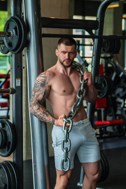 Handsome fit muscular caucasian man workout in the gym with weight pumping up muscles. Fitness and bodybuilding sport. Bodybuilder with dumbbells at gym, hard workout - Foto, afbeelding