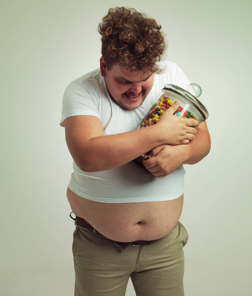Snoep maakt me gelukkig. een man met overgewicht met een grote pot snoep - Foto, afbeelding