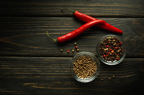 Lusky červené pálivé chilli papriček a koriandru na tmavém vinobraní kuchyňský stůl, horní pohled. Kulinářské pojetí aromatických potravin. - Fotografie, Obrázek