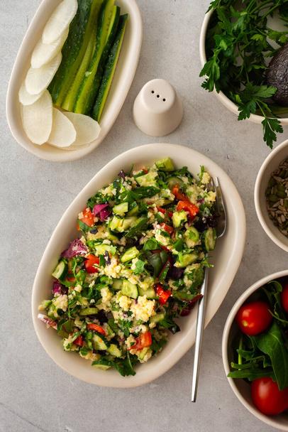 Gezonde lunch, gierstpap of quinoa met gemengde salade, tomaten en komkommers met peterselie en pompoenpitten, gezond eten, bovenaanzicht - Foto, afbeelding