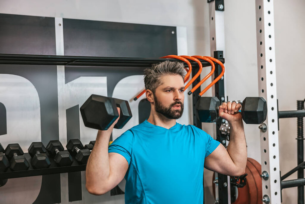 Workout with dumbbells. Serious athlete working with dumbbells - Fotó, kép