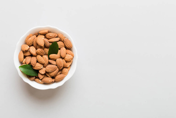 Fresh healthy Almond in bowl on colored table background. Top view. - Valokuva, kuva