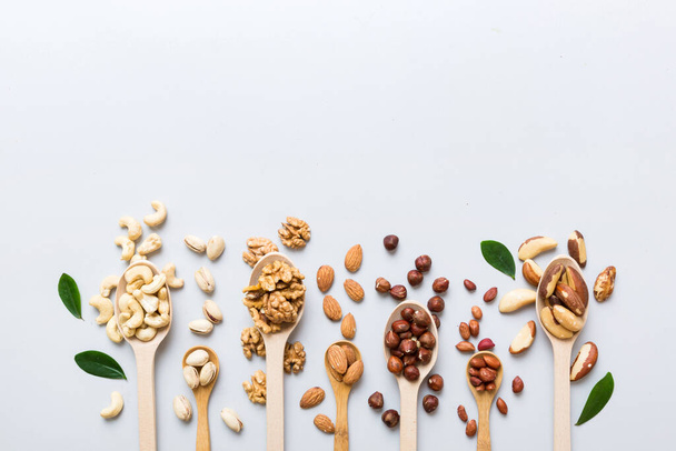 mixed nuts in white wooden spoon. Mix of various nuts on colored background. pistachios, cashews, walnuts, hazelnuts, peanuts and brazil nuts. - Foto, Bild