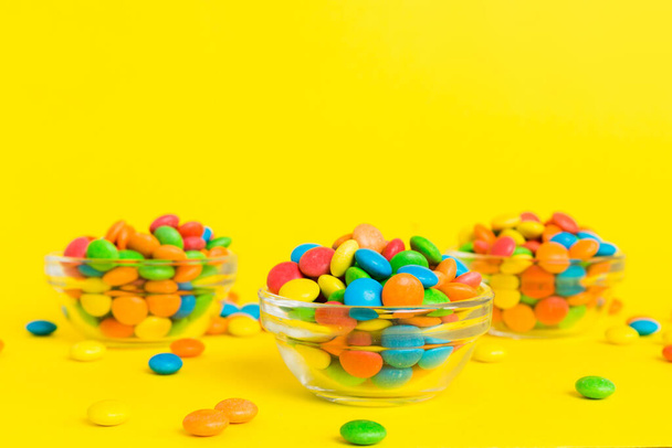 Multicolored candies in a bowl on a colored background. birthday and holiday concept. Top view with copy space. - Fotografie, Obrázek