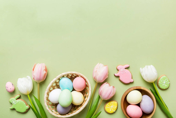 Cadre de Pâques avec œufs, boîte cadeau et tulipe sur un fond coloré. Le concept minimal. Vue du dessus Bonne composition de Pâques. Carte avec un espace de copie du lieu pour le texte. - Photo, image