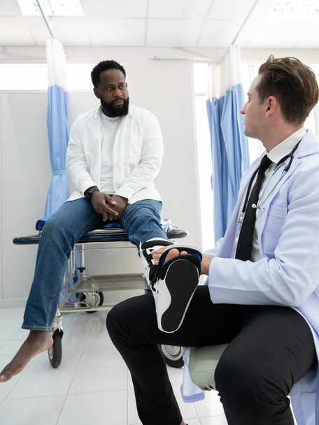 Lekarze badają czarnego pacjenta, który miał wypadek ze złamaną nogą w towarzystwie żony i dziecka.. - Zdjęcie, obraz