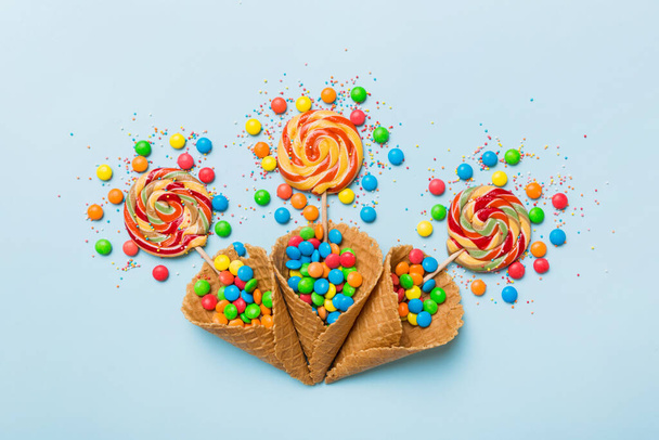waffle cone full of assorted traditional candies falling out on colored background with copy space. Happy Holidays sale concept. - Foto, Imagen
