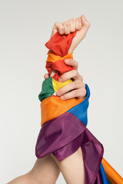 częściowy widok dłoni pary niebinarnej z flagą lgbt odizolowaną na szaro - Zdjęcie, obraz