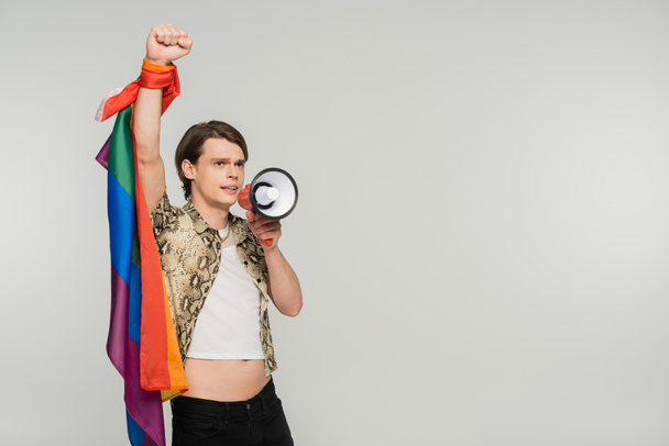 trendy bigender person with lgbt flag shouting in loudspeaker isolated on grey - Foto, imagen