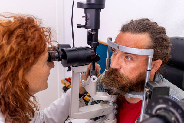 Red-haired optical doctor checks her hypster patient's eyesight - Fotoğraf, Görsel