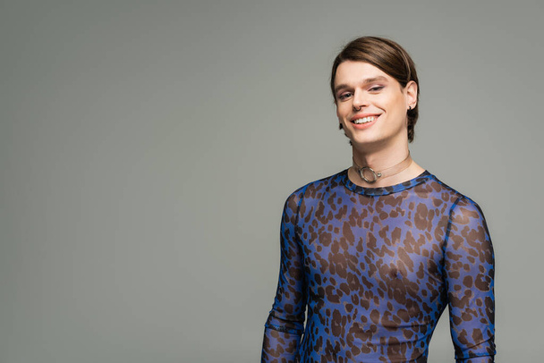 carefree pangender person in blue animal print top smiling at camera isolated on grey - Fotografie, Obrázek