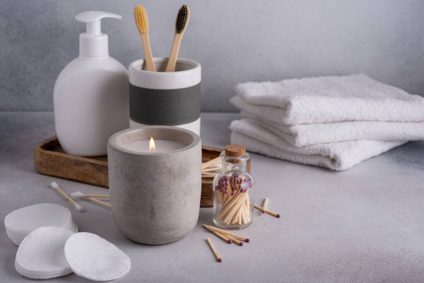 Scented candle and bathroom accessories: towels, dispenser and bamboo toothbrush. Modern bathroom decor. - Foto, afbeelding
