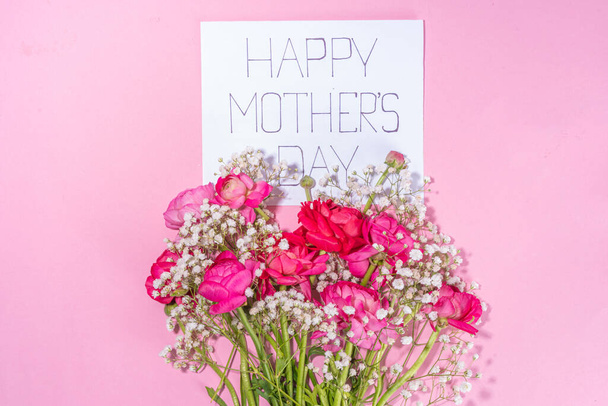 Moms day greeting card, invitation background, Spring bouquet of beautiful ranunculus flower, with cute craft paper gift bow and note Happy Mothers day, copy space on white background - Foto, Imagem