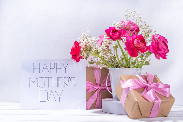 母の日の挨拶カード、招待状の背景、美しいランヌクルスの花の春の花束、かわいいクラフト紙のギフト弓と注意してください幸せな母の日、白い背景にスペースをコピー - 写真・画像