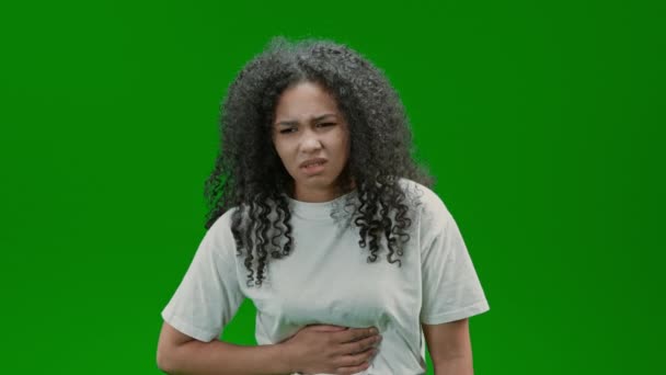 kobieta z kręconymi długimi włosami ubrana biała koszula cierpi na ból brzucha Izolowane na zielonym ekranie - Materiał filmowy, wideo