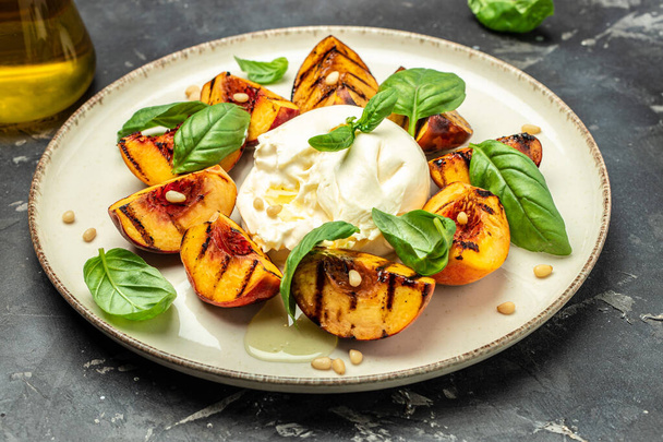 Gourmet Roasted Peaches with Burrata soft cheese, basil and drizzled with honey, with rose wine. Antipasto Dinner or aperitivo party. - Zdjęcie, obraz