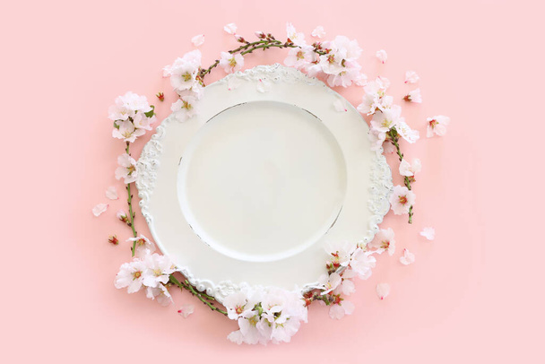 Top view of vintage white empty plate over spring cherry tree flowers. Flat lay - Foto, afbeelding