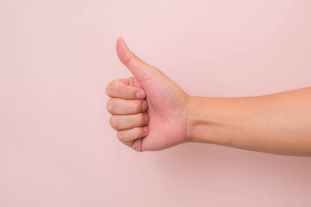 Close up of male hand showing thumbs up symbol on pink background. - Fotó, kép