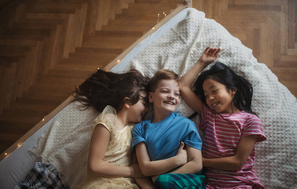 Top view of three happy friends lying in bed. - Foto, Imagen
