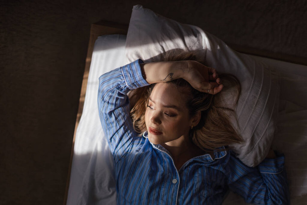 Top view of woman lying in a bed,morning sun shining on her face. - Foto, imagen