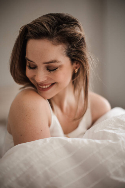 Portrait of young woman at morning in a bed. - 写真・画像