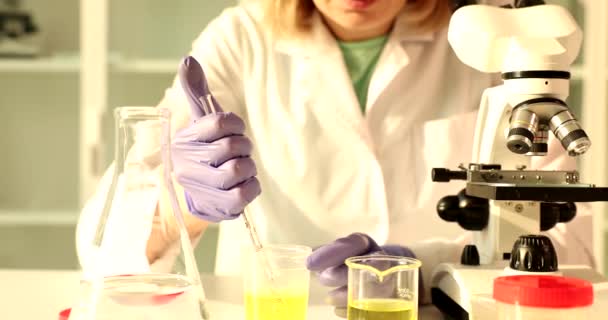 Kemialliset neste tippuu lääkärin tai tiedemies tutkii mikroskoopilla laboratoriossa. Mikrobiologisen tutkimuksen käsite - Materiaali, video