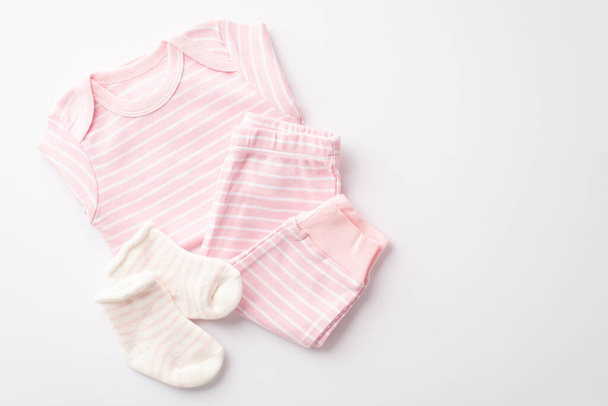 ベビーシャワーの概念。ピンクの幼児服のシャツのズボンとソックスのトップビューの写真隔離された白い背景 - 写真・画像