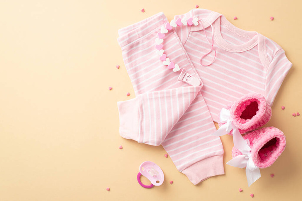 赤ん坊の女の子の概念。幼児服のトップビュー写真ピンクのシャツパンツニットブーティーダミー歯チェーンとスプリンクルで隔離されたパステルイエローの背景に空のスペース - 写真・画像