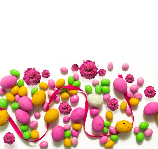 バラ色のカラードラッグとチョコレートの卵。イースターのお菓子の背景 - 写真・画像