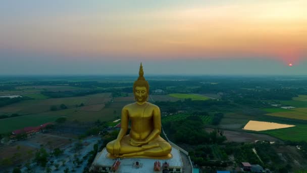 εναέρια θέα hyperlapse τοπίο κίτρινο ουρανό στην ανατολή του ηλίου πάνω από το χρυσό μεγάλο Βούδα.. το χρυσό Βούδα στο ψηλό βουνό στο wat Ta It Phetchaburi.. φωτεινό κίτρινο ουρανό πάνω από Phetchaburi φόντο της πόλης. - Πλάνα, βίντεο