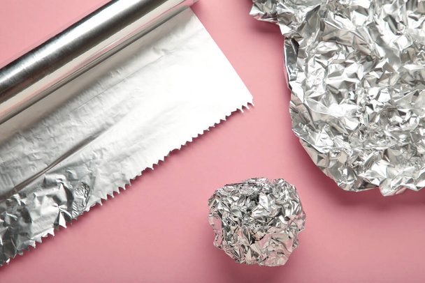 Foil ball with aluminium rolls on pink background. Top view - Foto, Imagen