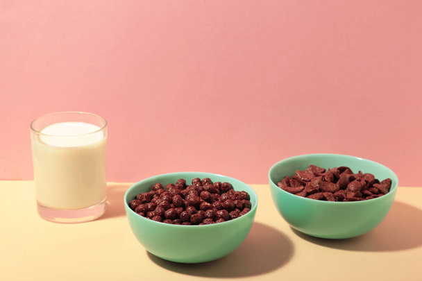 Set of various breakfast cereals with glass of milk on pink background. Top view - Fotó, kép