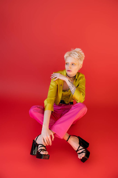 full length of young albino model in trendy clothes posing on carmine pink  - Foto, Bild