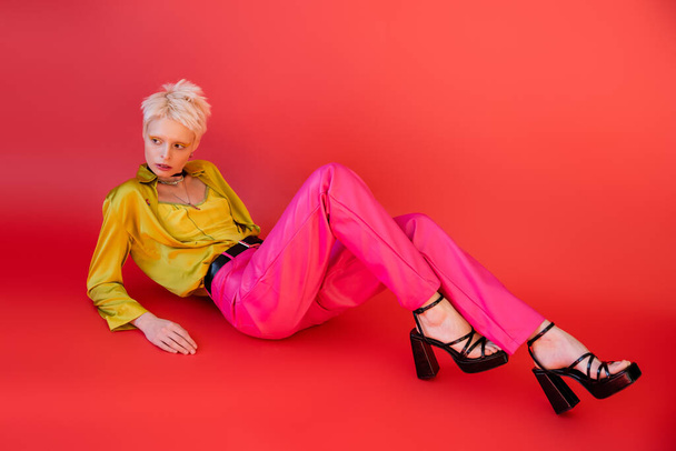 full length of albino woman in heeled sandals and trendy clothes posing on carmine pink  - Photo, Image