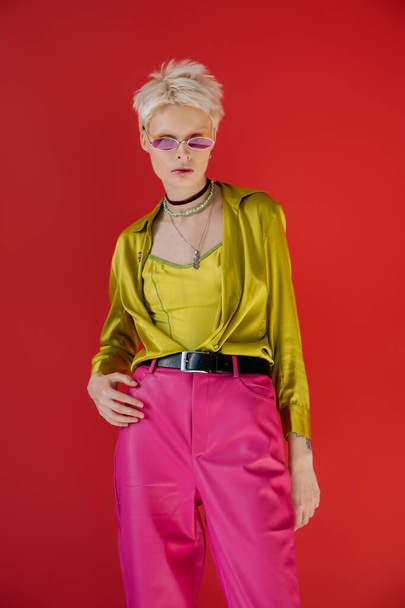 tattooed albino model in stylish outfit and sunglasses posing on carmine pink   - Zdjęcie, obraz